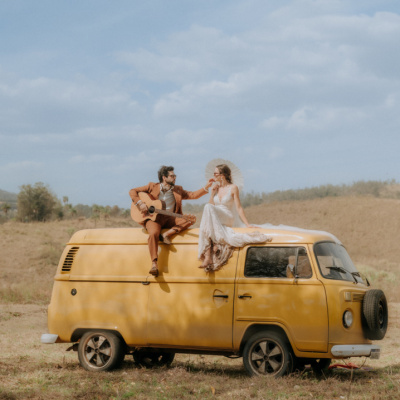 Destination wedding photo on vintage van with groom playing guitar