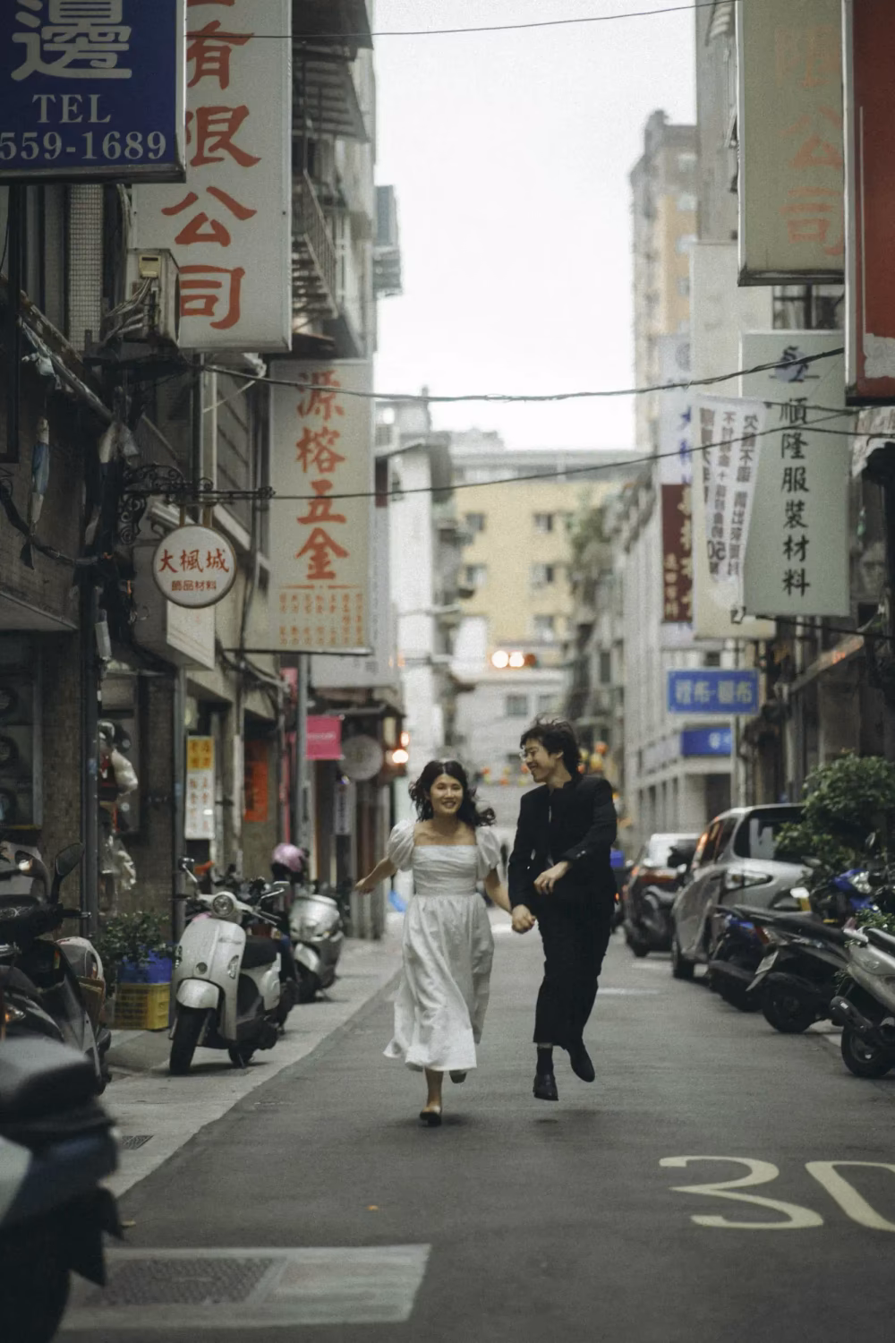 Couple holding hands running through street of Chinatown