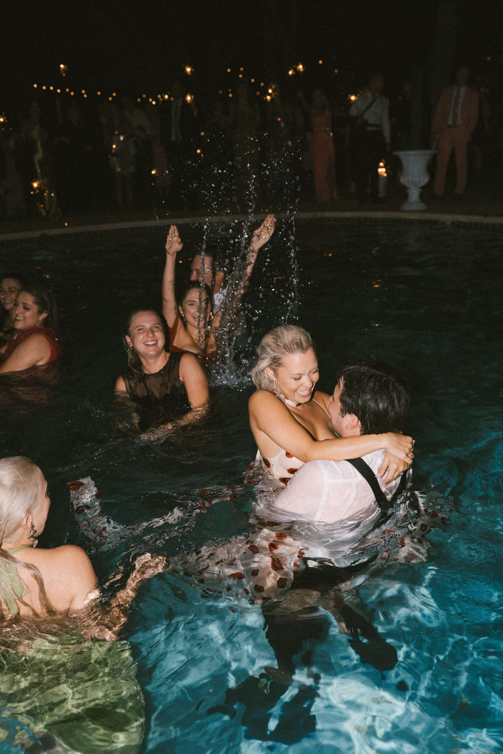 couple and wedding guests in swimming pool